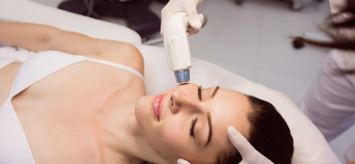 Dermatologist giving facial massage to patient through soniclifting in clinic